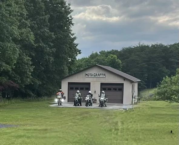 Three Moto Guzzi Guardias and a Stelvio parked outside a garage marked Moto Grappa